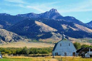 Tranquil Montana countryside featuring a white barn with stunning mountain backdrop.